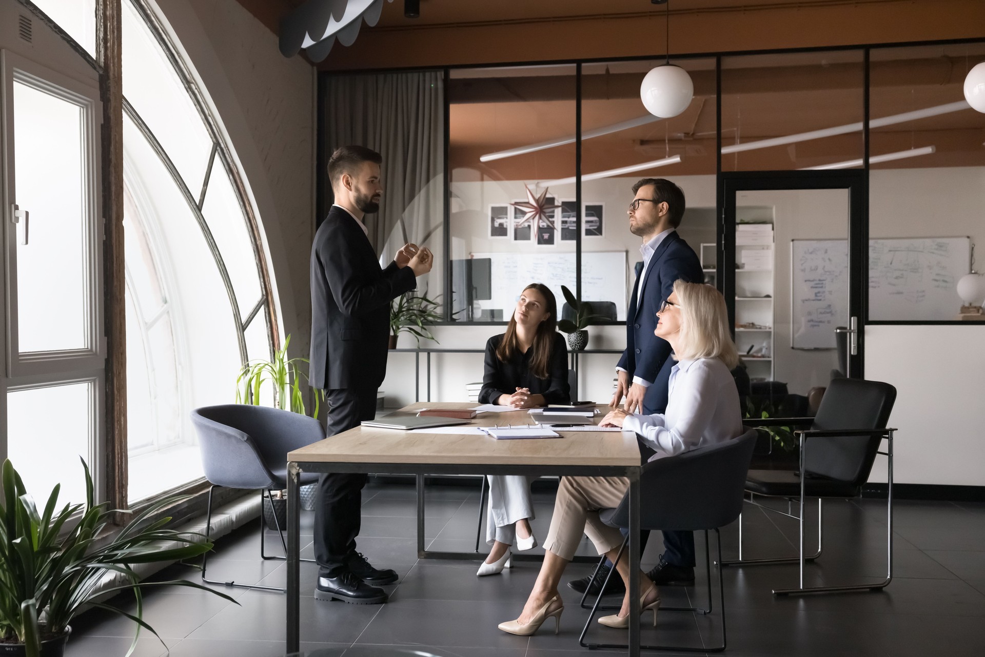 Serious team leader talking to colleagues gathered in boardroom